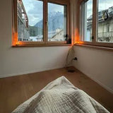 Couverture sur un lit devant une fenêtre avec vue sur la montagne