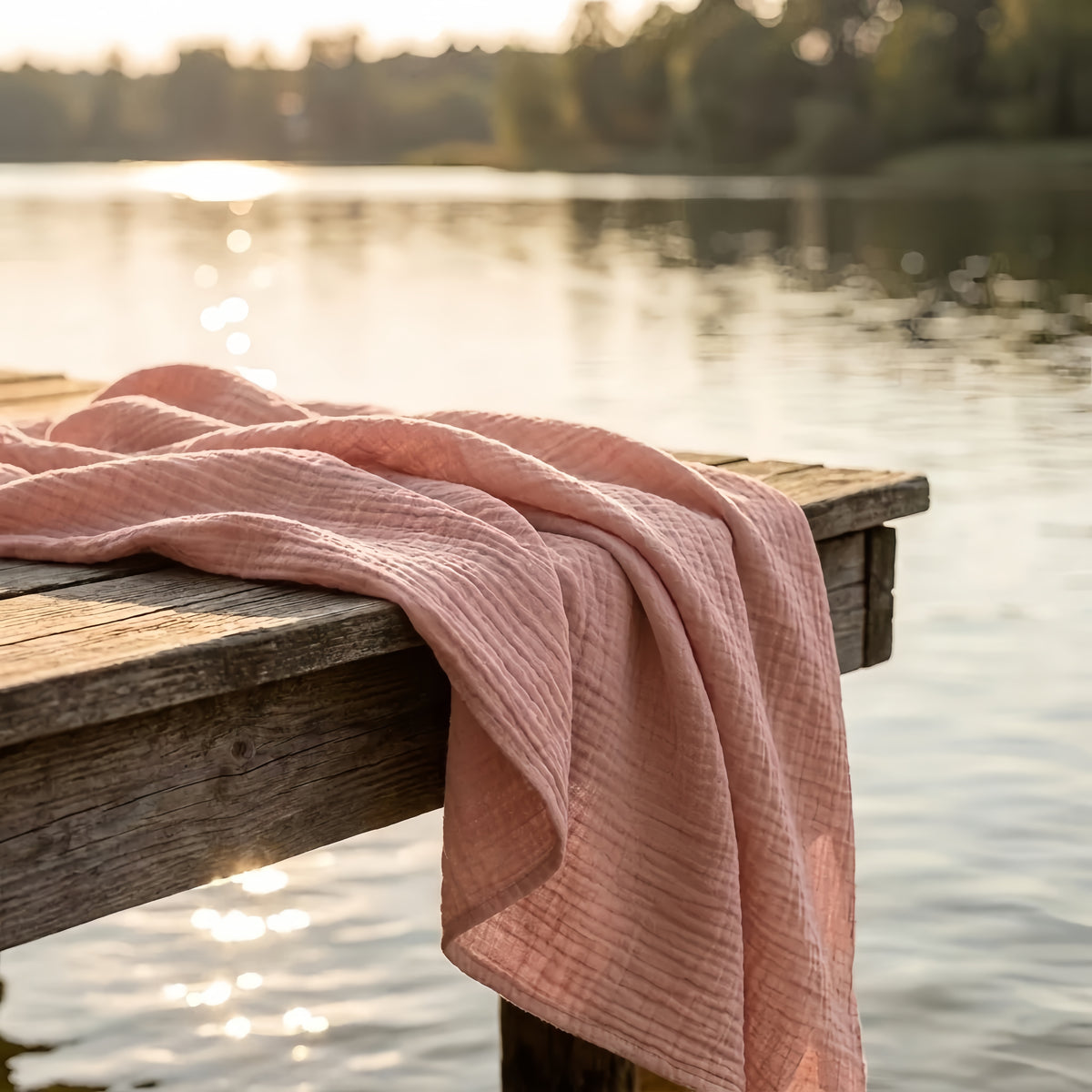Couverture en mousseline posée sur un ponton au bord d'un lac au coucher du soleil
