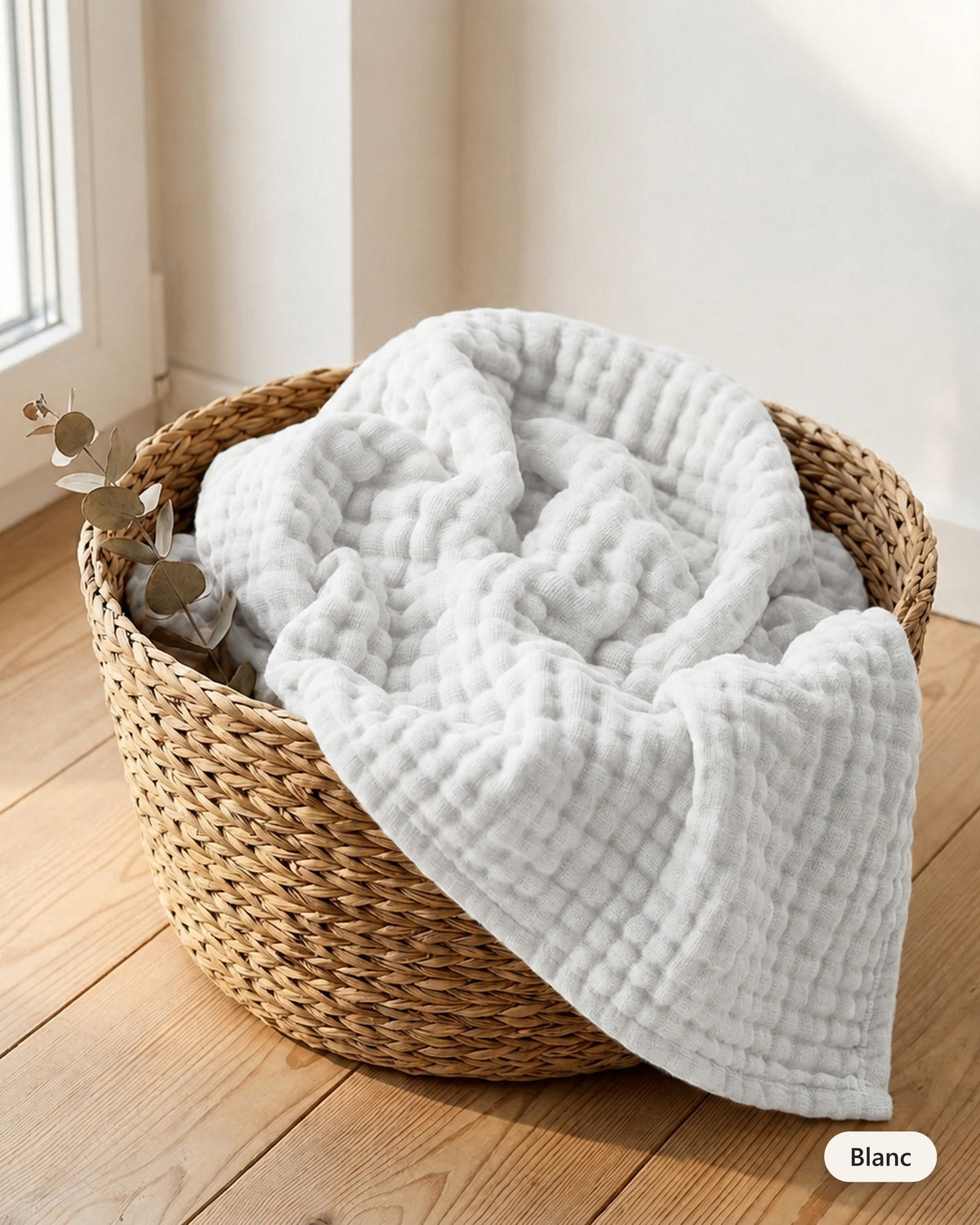 Couverture en mousseline coloris Blanc dans un panier en fibre naturelle