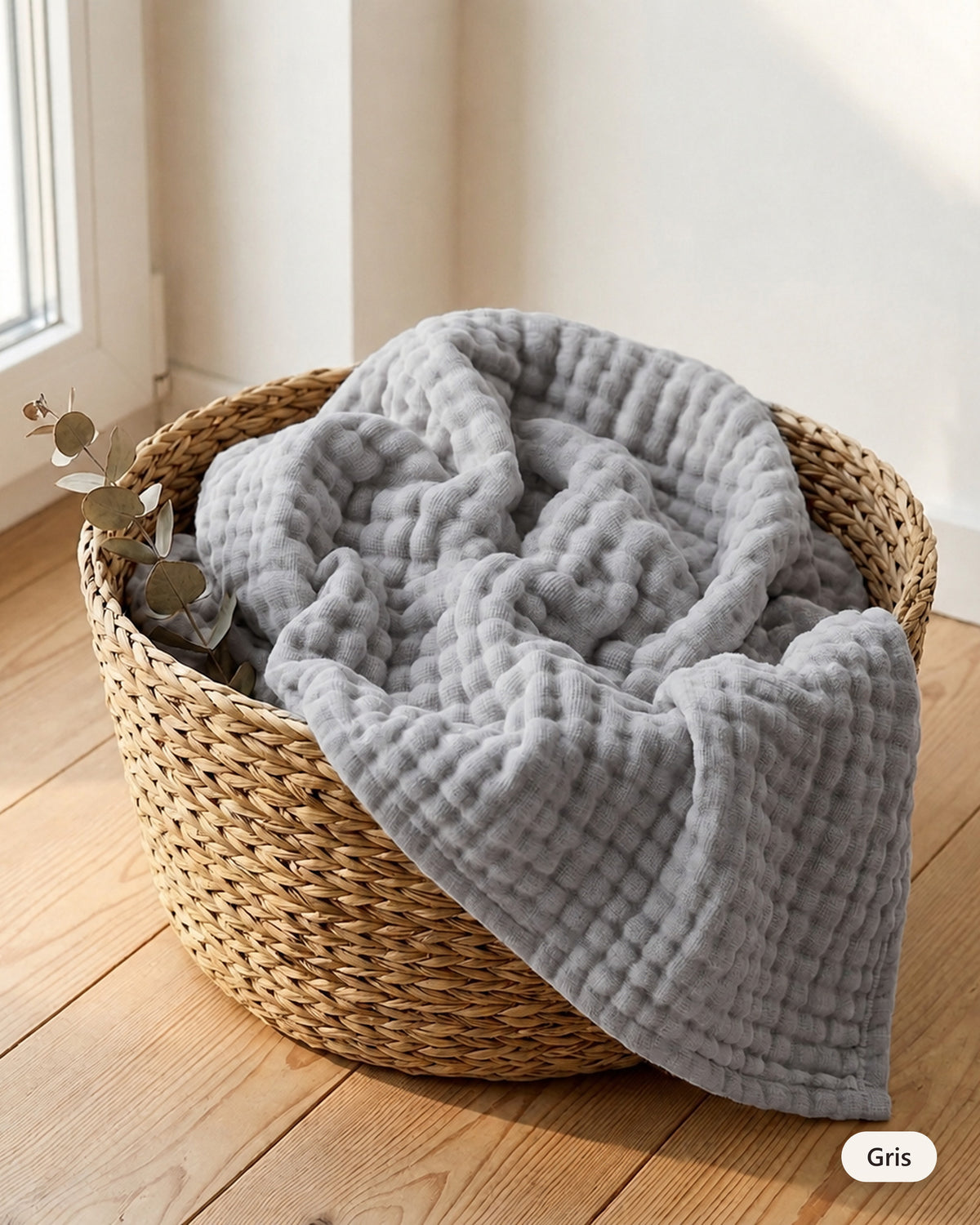 Couverture en mousseline coloris Gris dans un panier en fibre naturelle