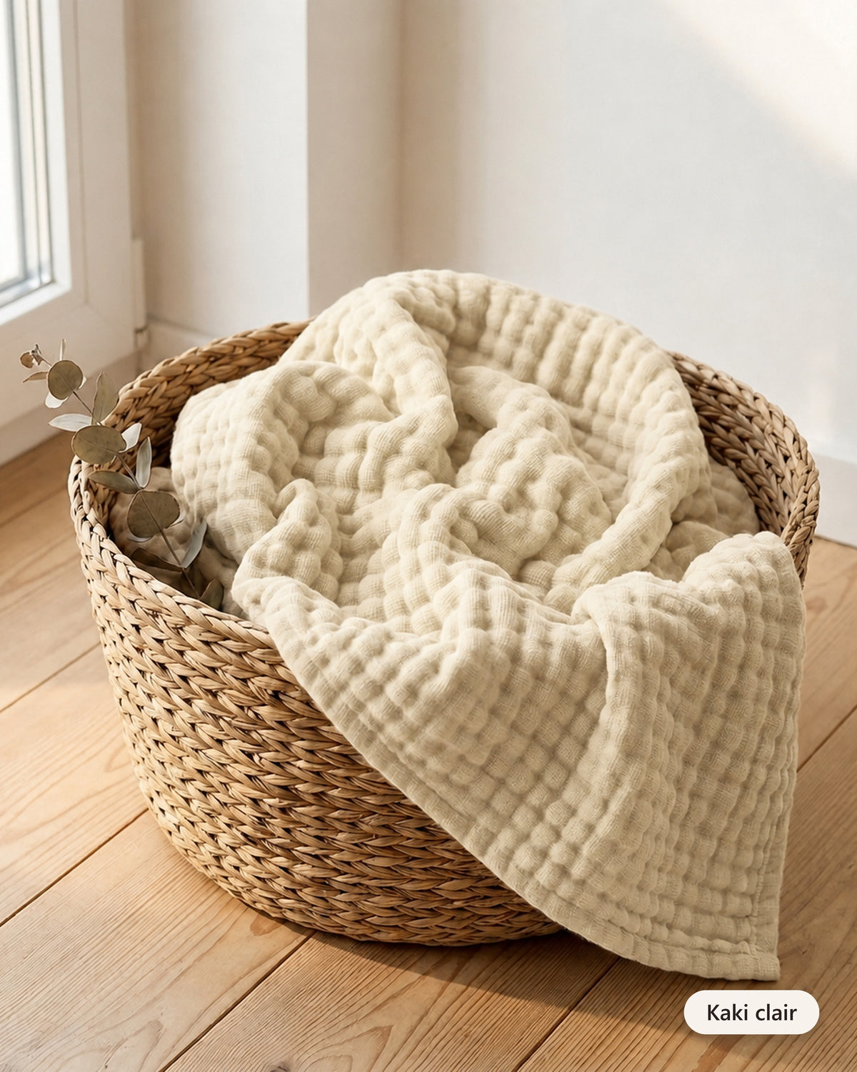 Couverture en mousseline coloris Kaki clair dans un panier en fibre naturelle