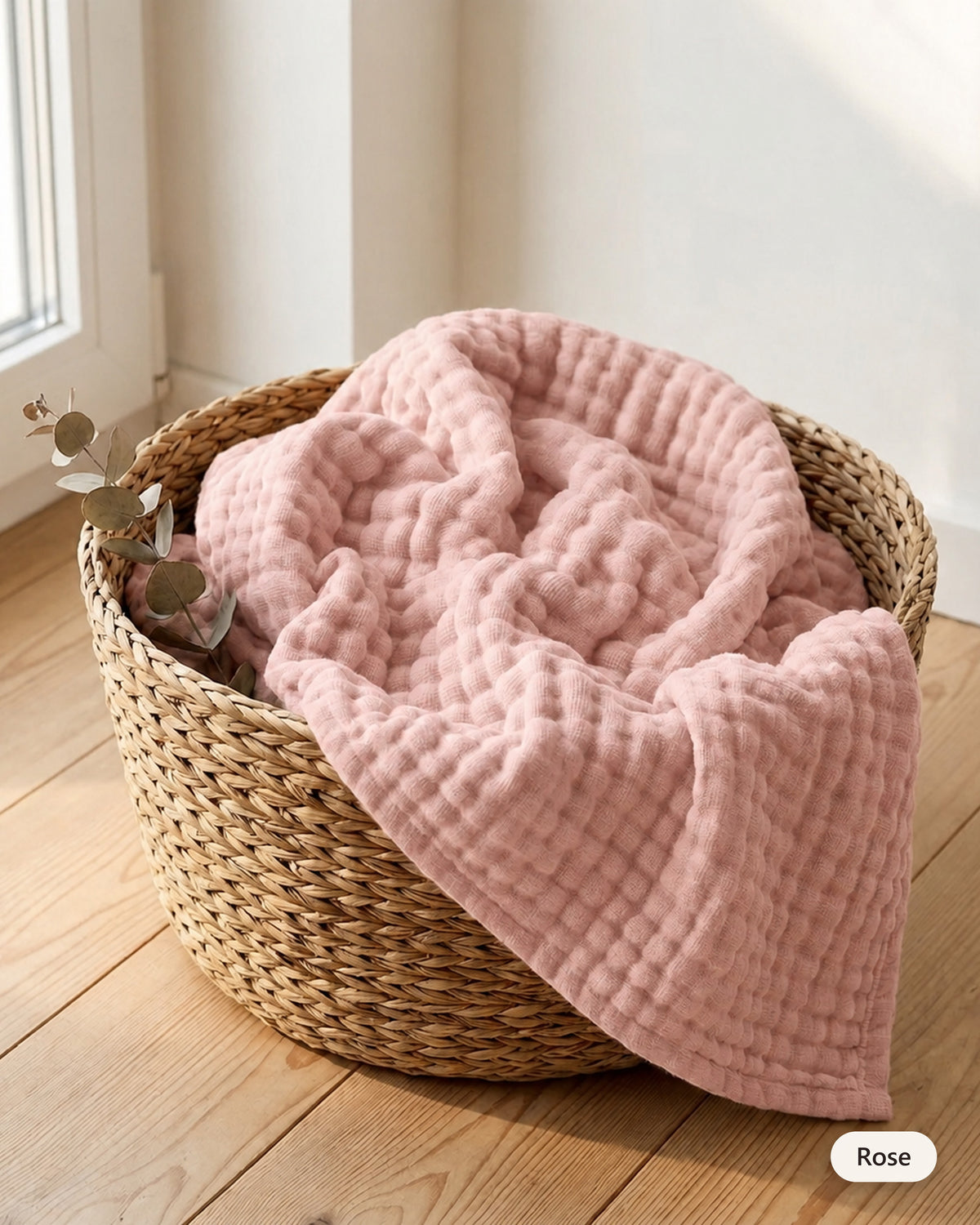 Couverture en mousseline coloris Rose dans un panier en fibre naturelle