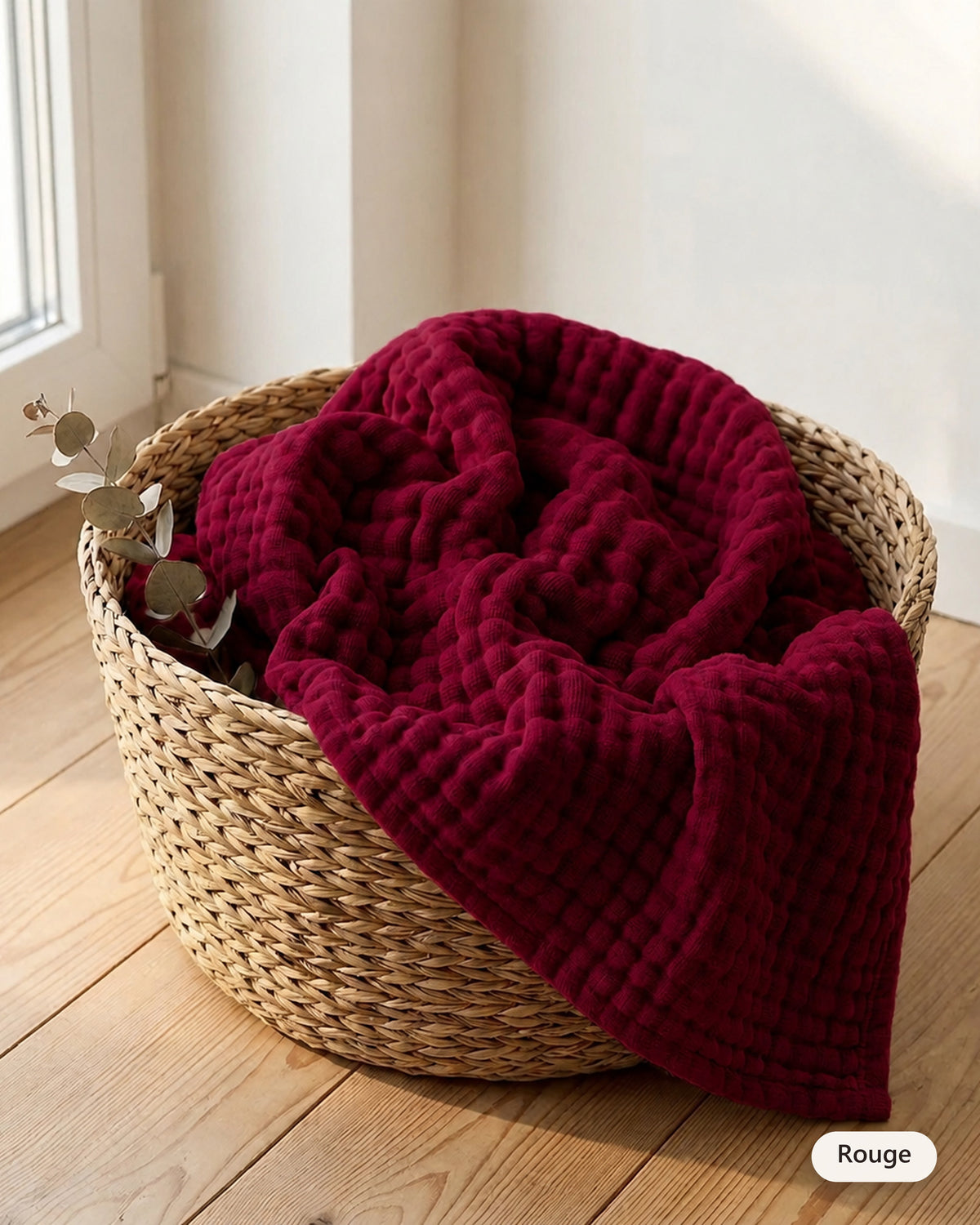 Couverture en mousseline coloris Rouge dans un panier en fibre naturelle